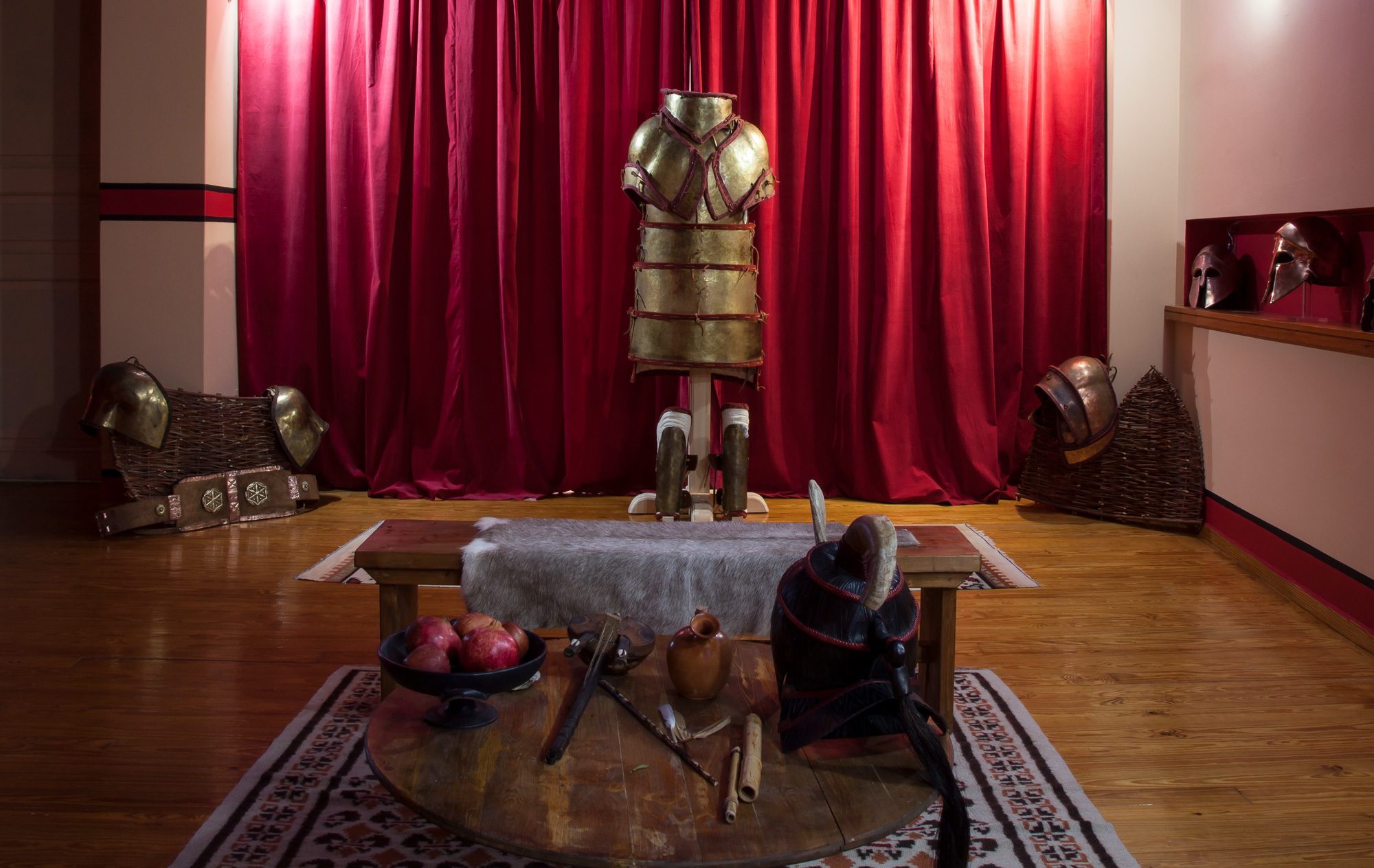 Armour and equipment installation inside the atelier | Archaeopolis Atelier & Showroom Reconstructed armour, helmets and equipment arranged around a low table inside the Archaeopolis atelier