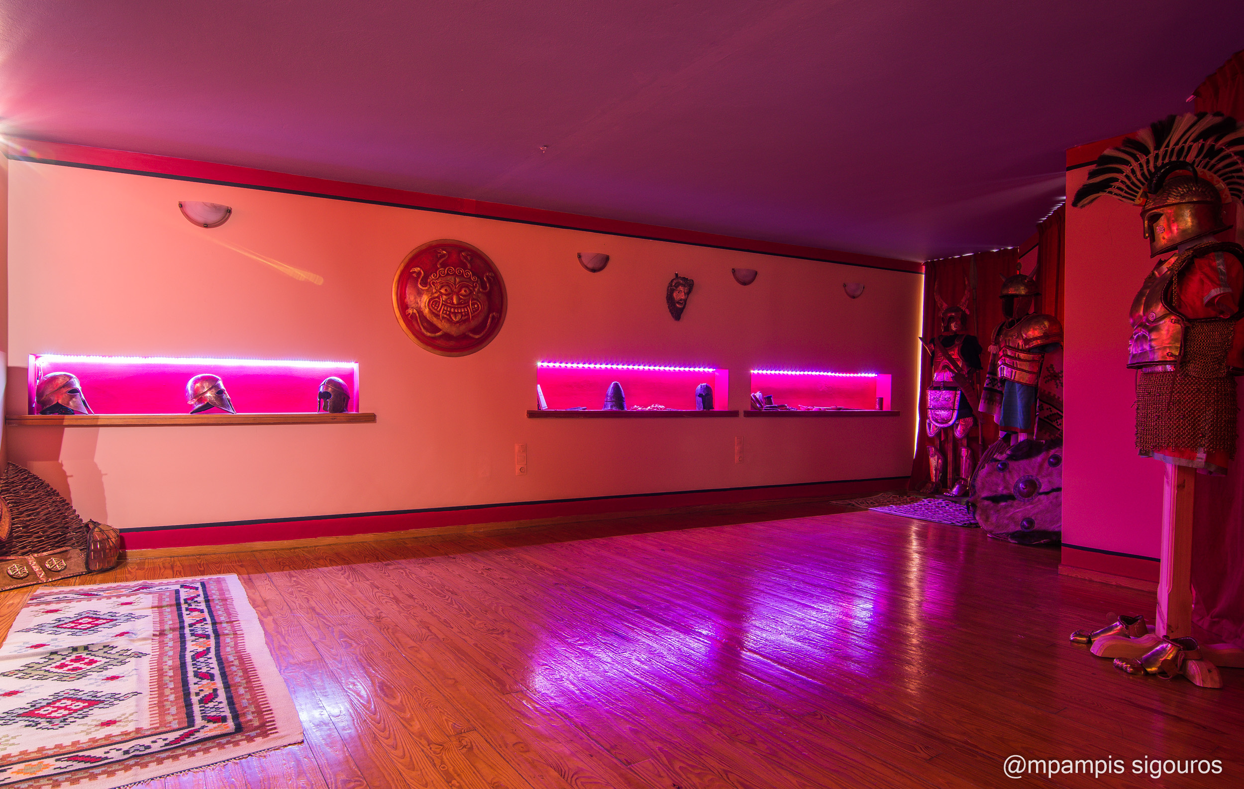 Helmet gallery and full armour displays | Archaeopolis Atelier & Showroom Wide interior of the Archaeopolis showroom with illuminated helmet displays and full armour ensembles