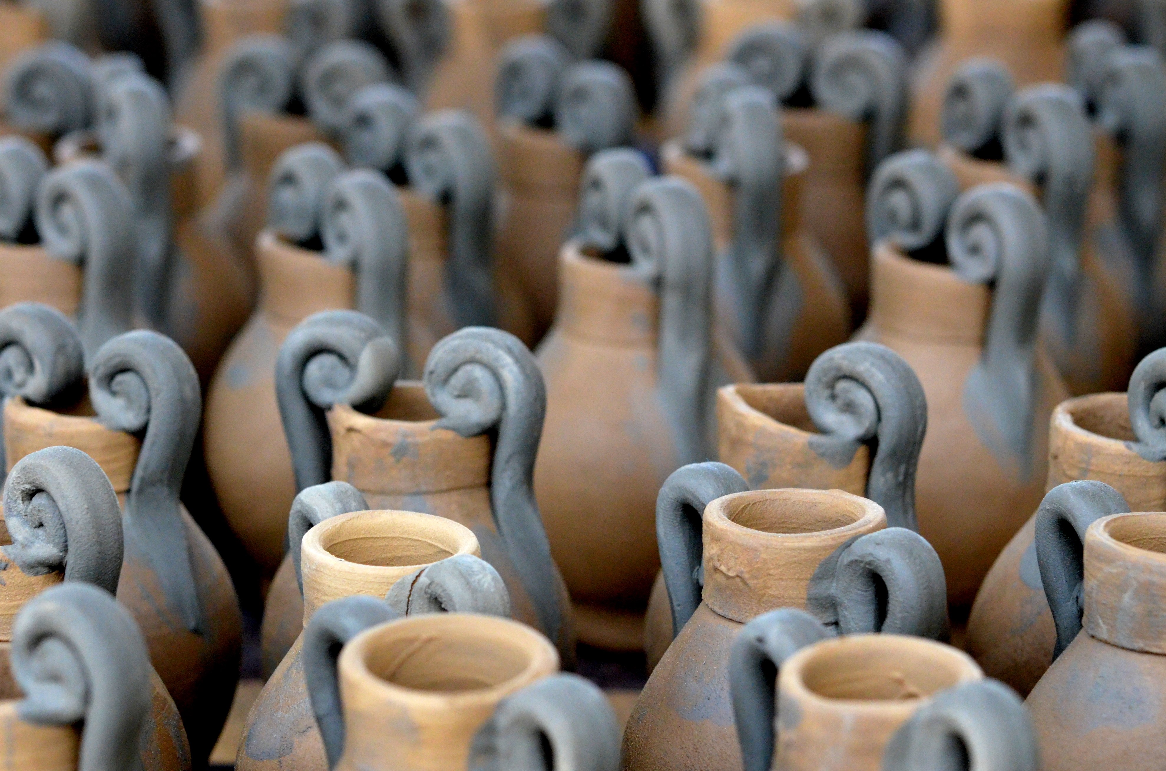 Rows of newly formed clay vessels with high curled handles drying together