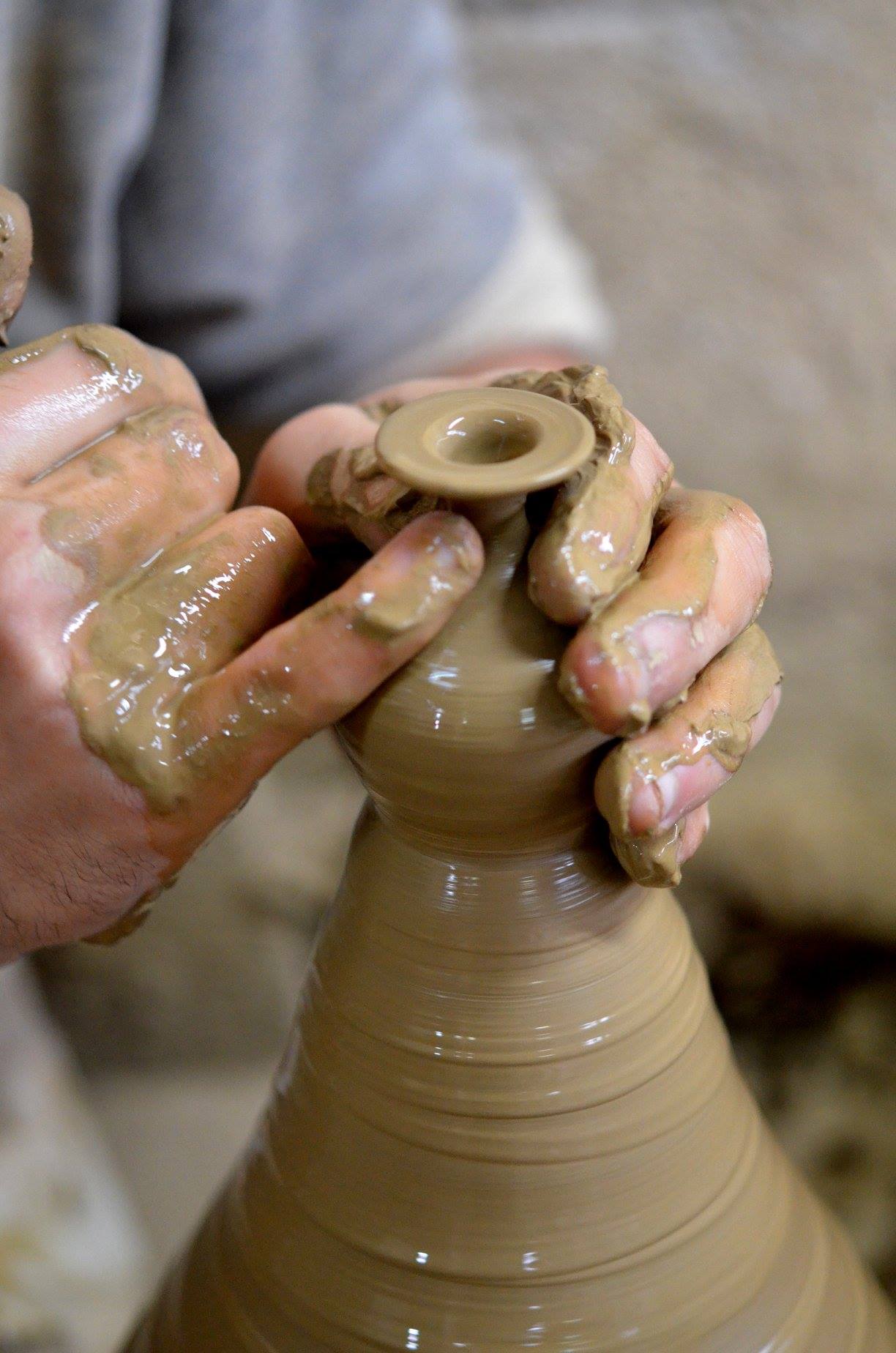 Potter refining the rim and neck of a wet clay vessel by hand