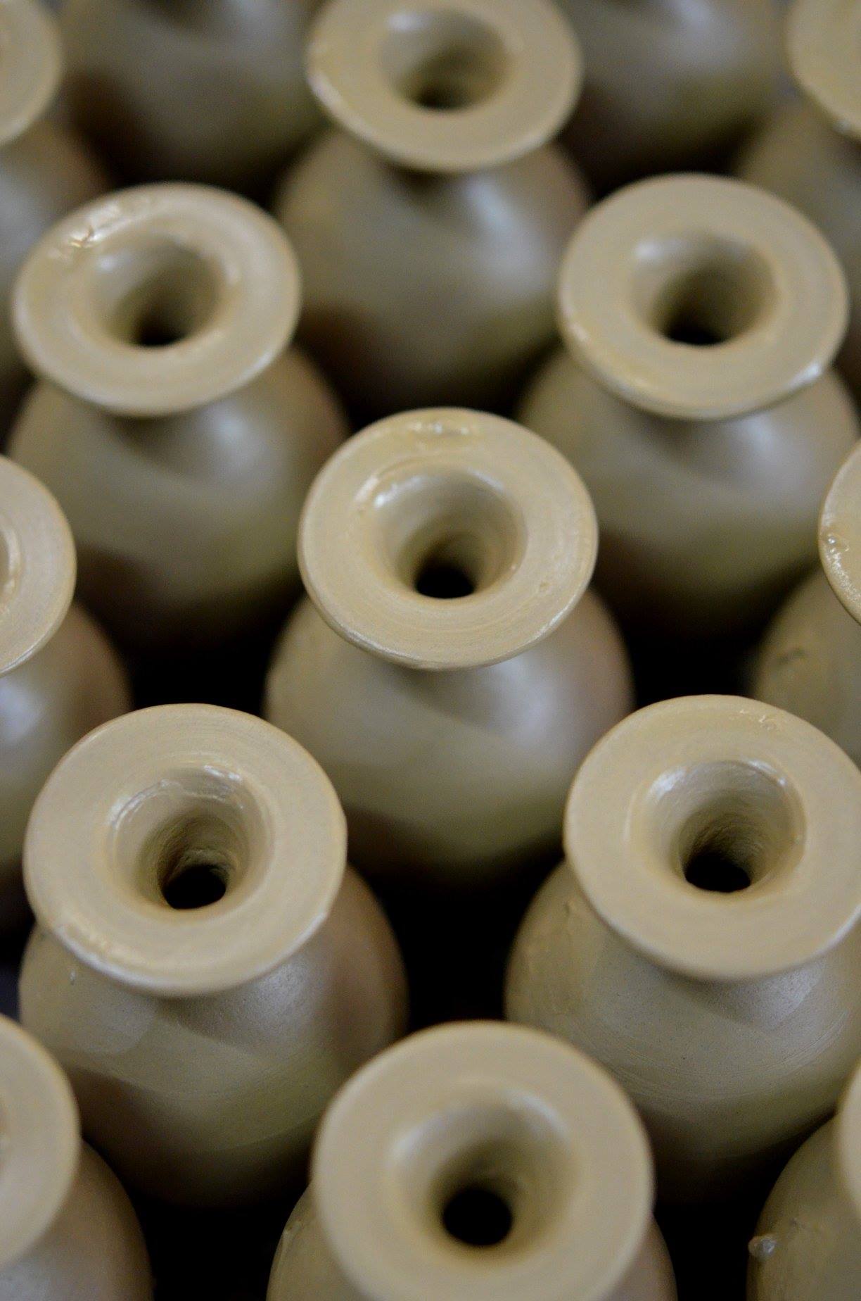 Group of small narrow-necked clay vessels arranged together after forming