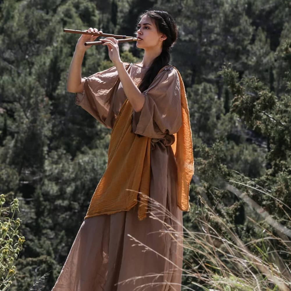 Female performer playing a reconstructed wind instrument outdoors