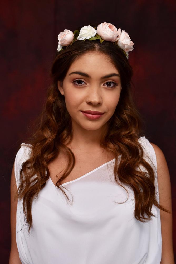Portrait of a young woman in white dress wearing a floral crown
