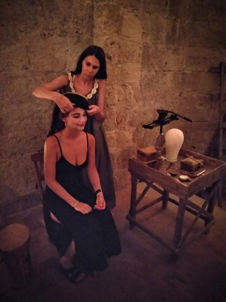 Two women in dark dresses performing a candlelit ritual scene