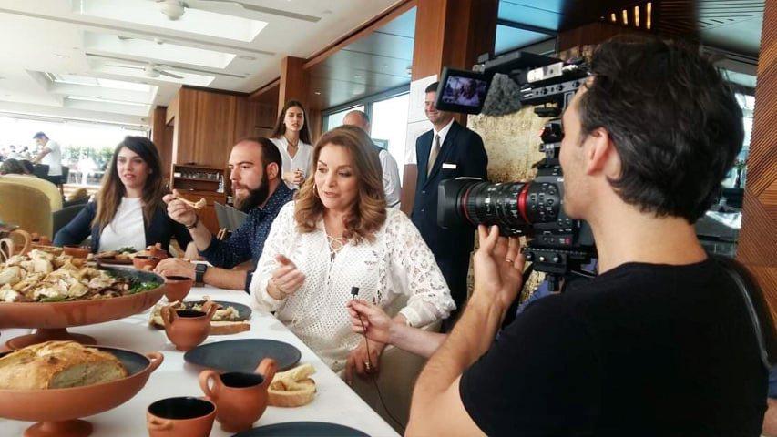 Film crew recording women and guests around a table of reconstructed historical food