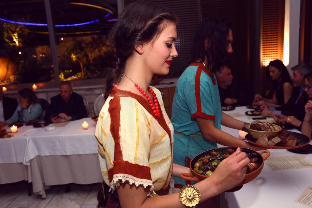 Costumed woman serving dishes during an immersive historical dining experience