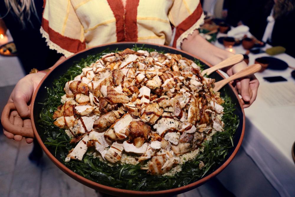 Close view of a plated reconstructed historical dish carried by a costumed server