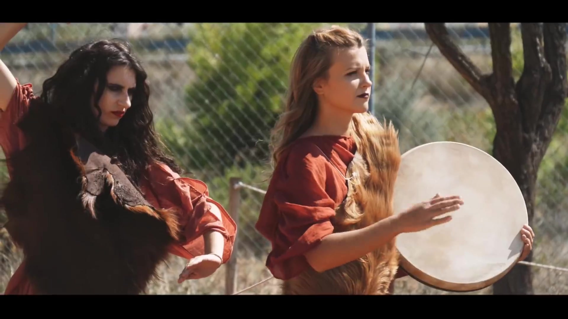 Two women in historical dress performing together with a large frame drum