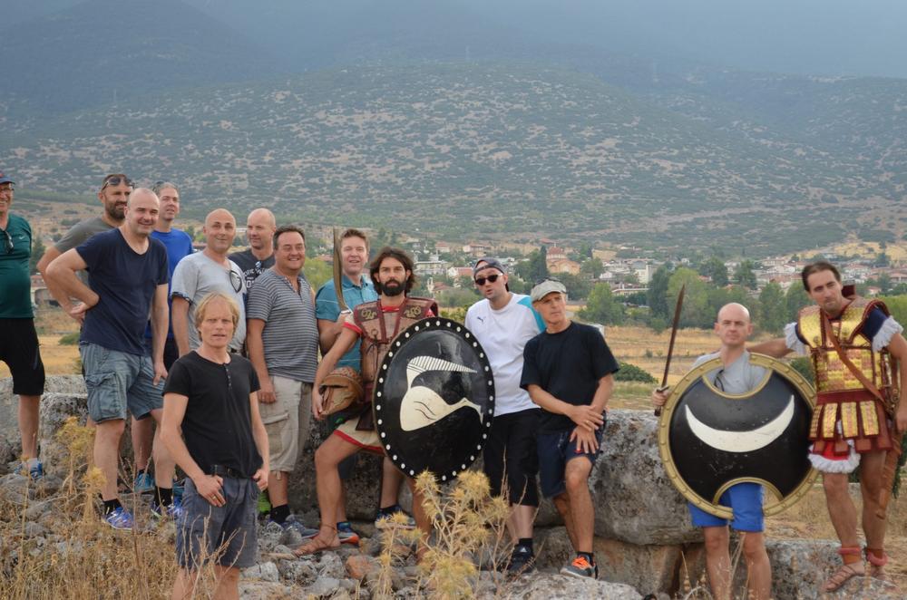 Visitors and equipped interpreters gathered at a mountain overlook with round shields