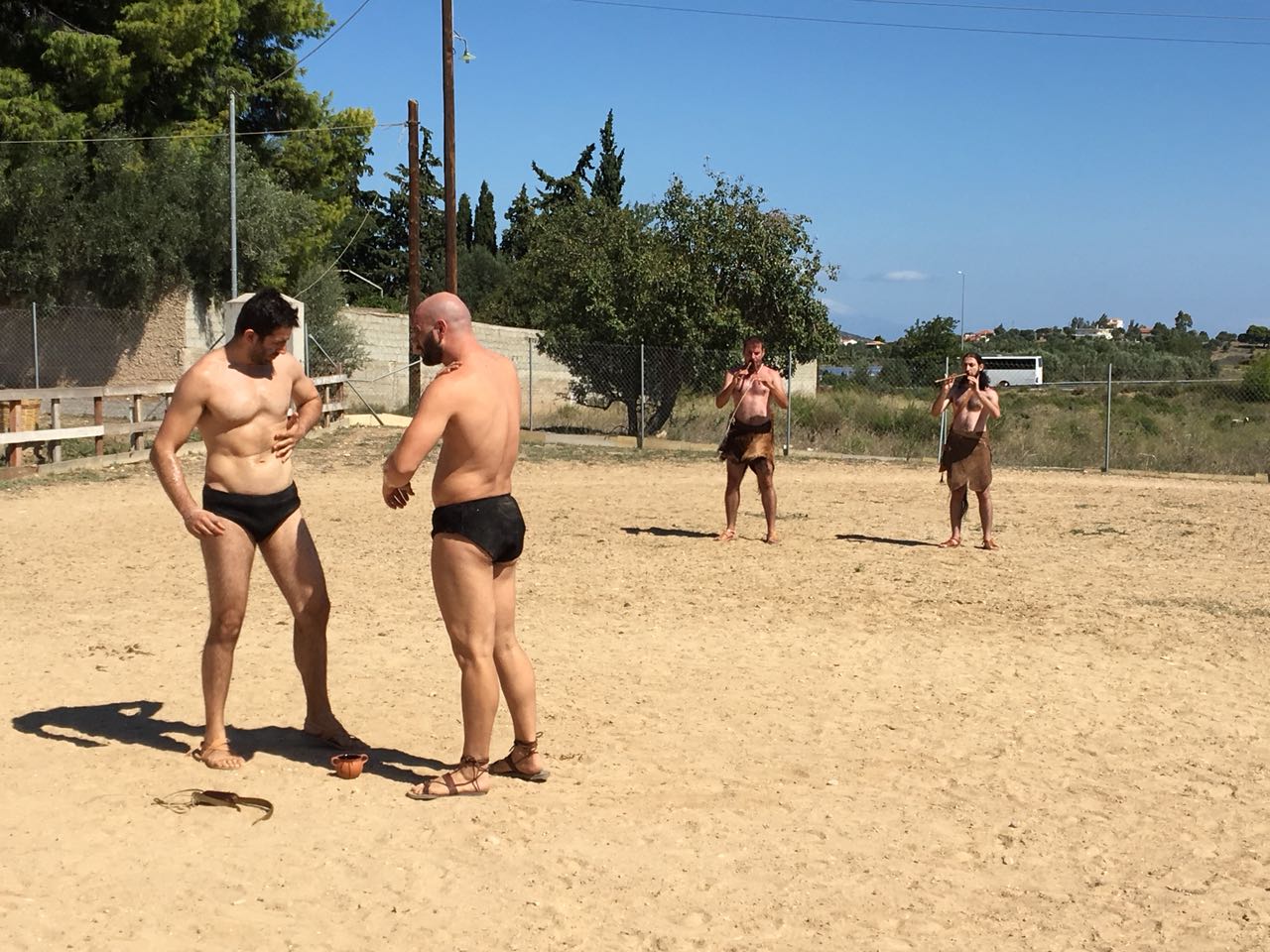 Two athletes engaging in a standing grapple during an outdoor pankration demonstration