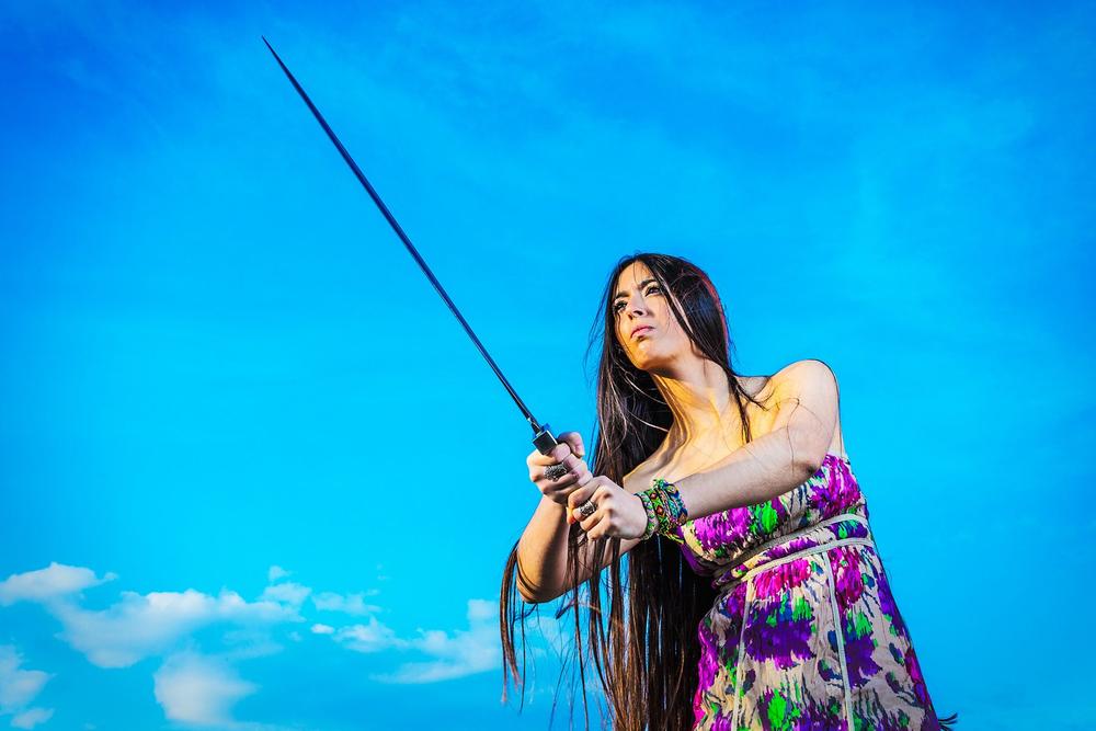 Female historical character holding a long spear against a blue background