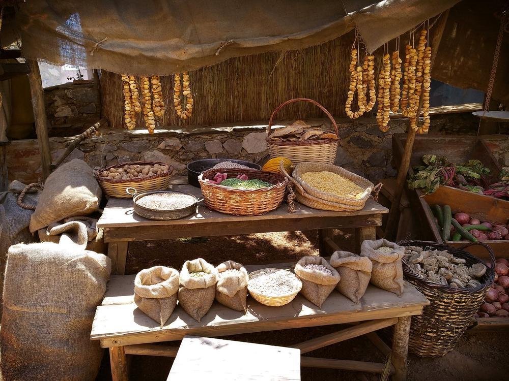Historical dry-goods stall with grains, legumes, baskets and serving vessels