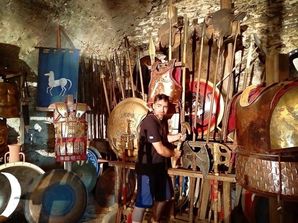 Camera operator filming inside a densely stocked armoury workshop set