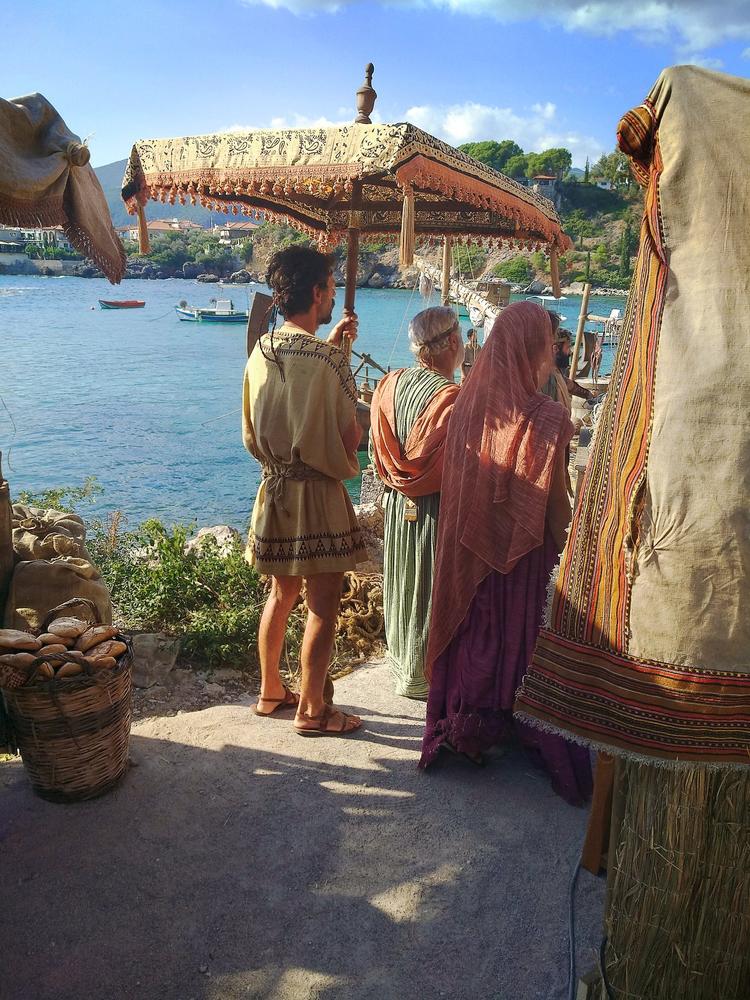 Costumed historical characters looking across a coastal market environment