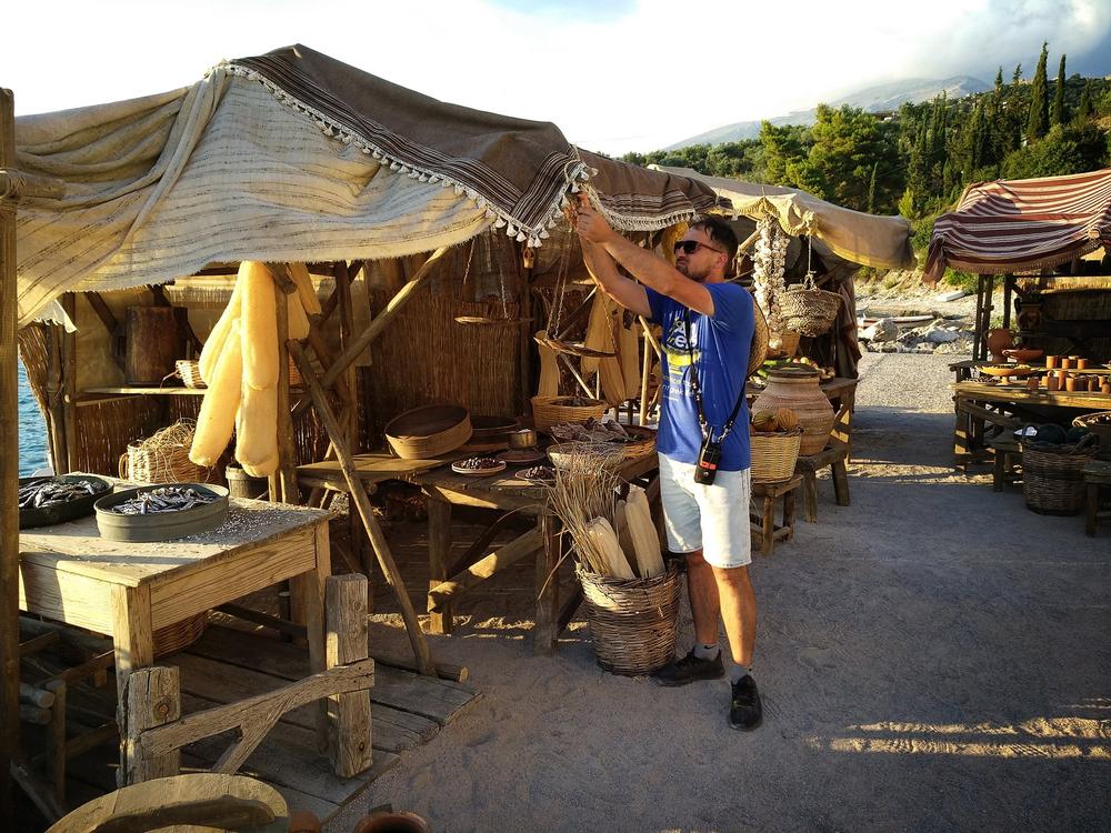 Crew member working among timber stalls during construction of an open-air historical market set