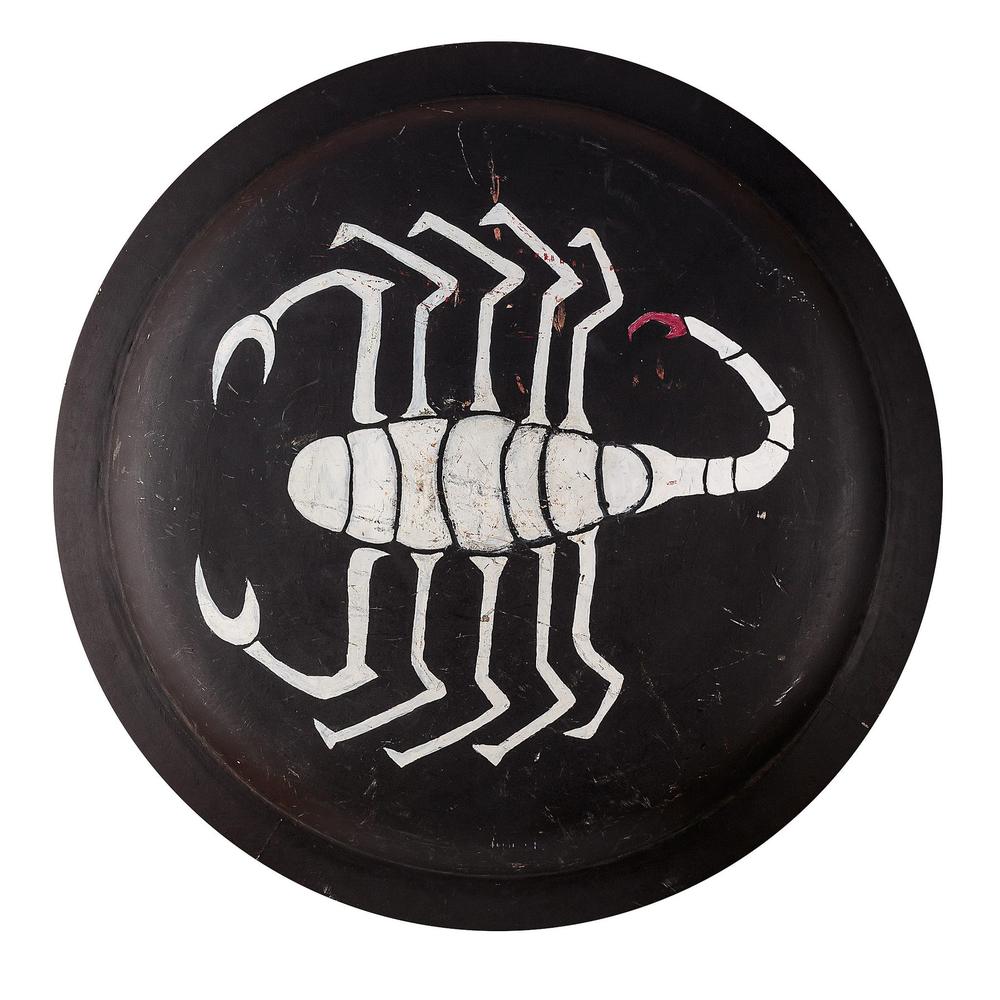 Round black shield painted with a white scorpion emblem