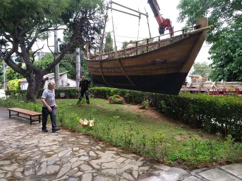 Reconstructed Archaeopolis Olkas vessel suspended by crane during installation