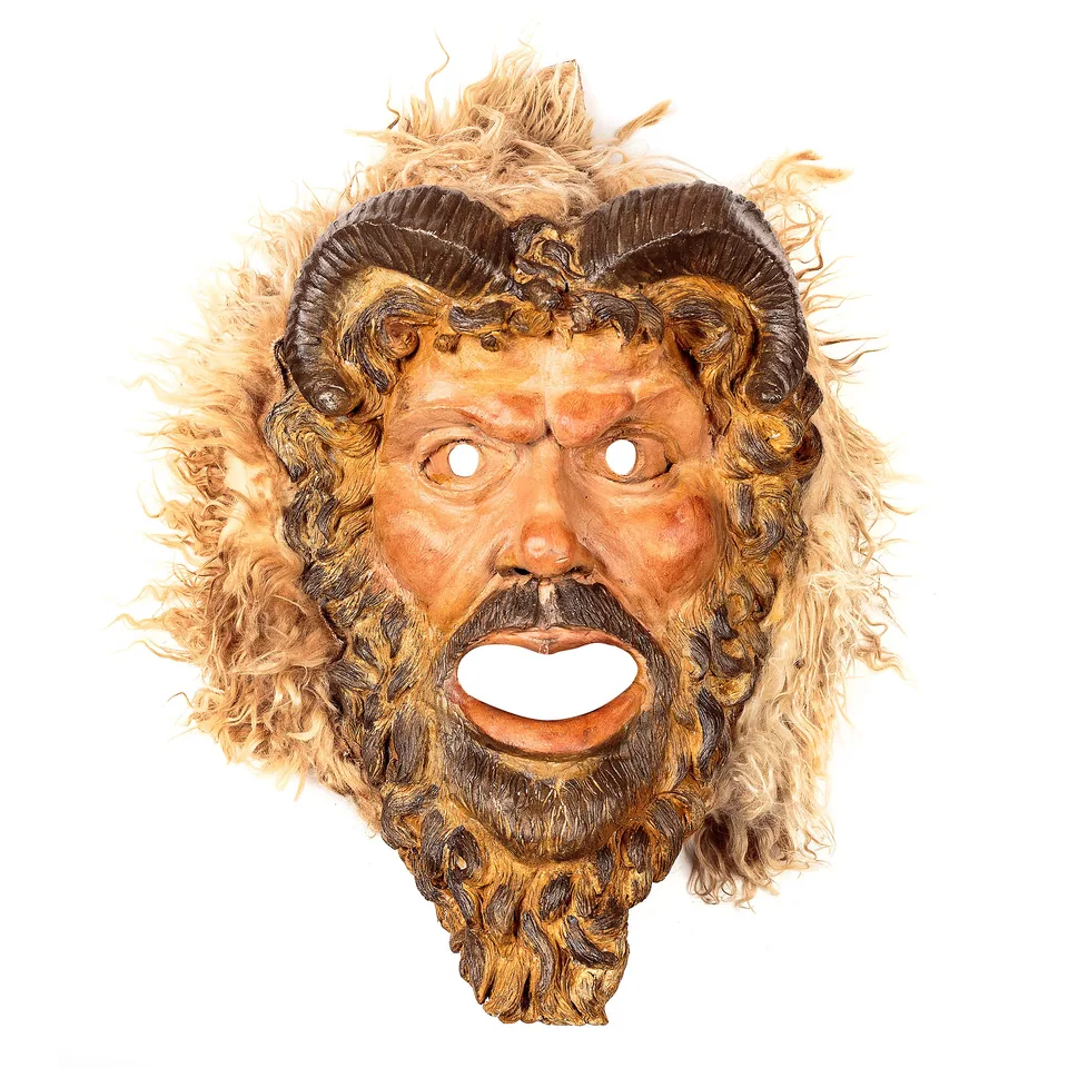 Bearded mask with curved ram horns surrounded by pale woolly hair
