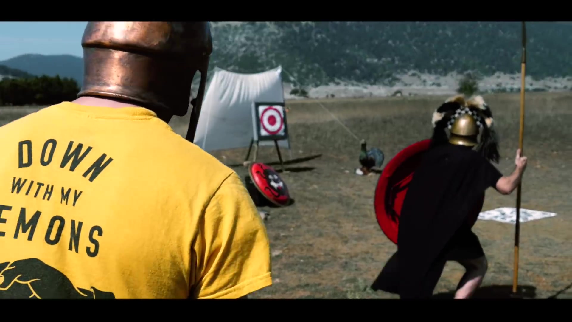 Archery and protective equipment in the field | Archaeopolis Archery Games Archer and shield-bearing interpreter beside the target range
