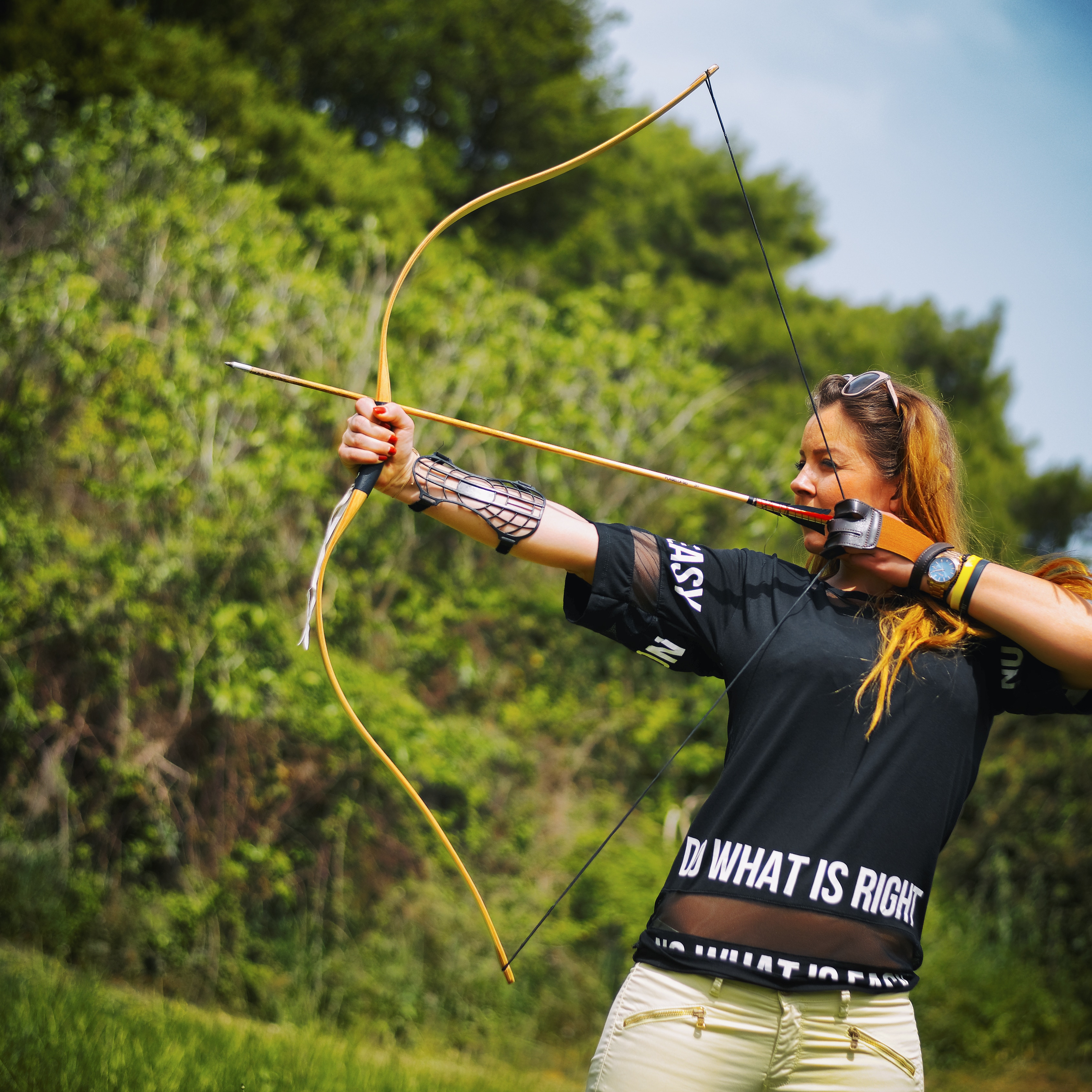 Female archer drawing a traditional bow outdoors