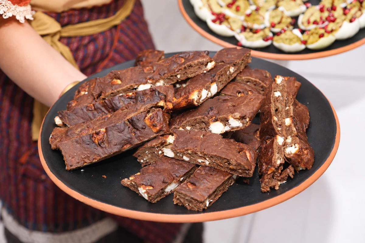 Dark baked slices with white pieces on a platter held for serving.