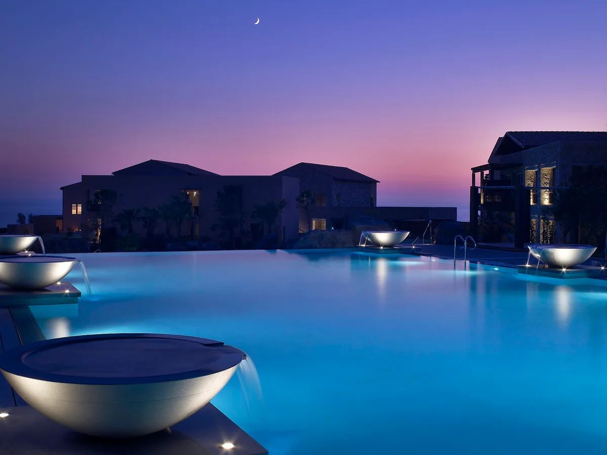 Illuminated resort swimming pool at dusk at Costa Navarino in Greece