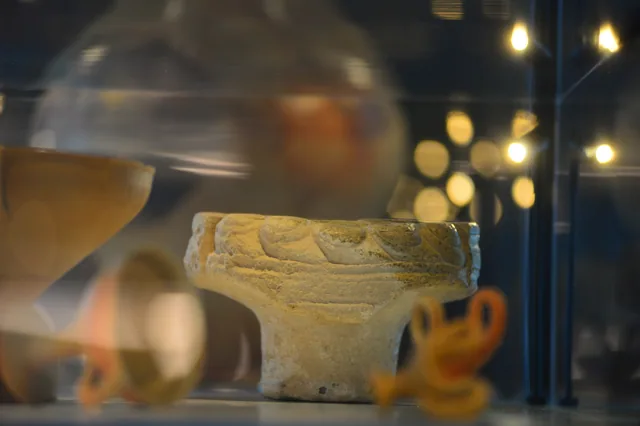 Pale clay vessel with raised decoration around its rim.