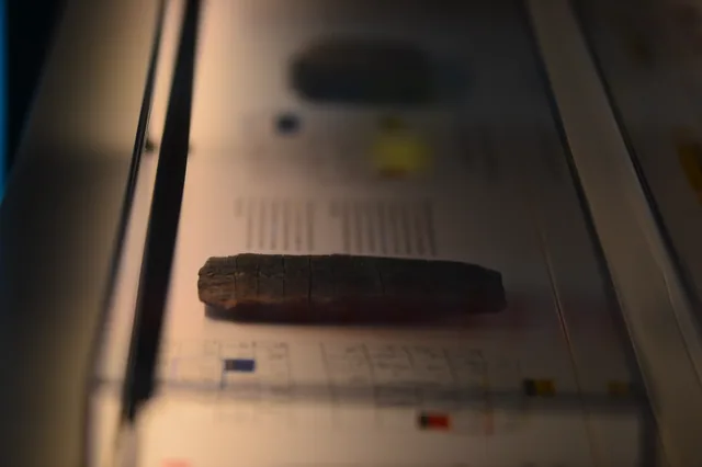 Close-up of an elongated clay tablet bearing rows of incised signs.