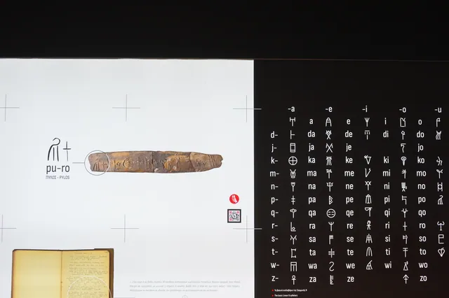 Museum panel explaining Linear B writing, including the syllabic spelling of Pylos and a clay tablet.