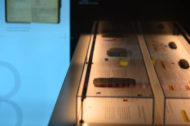 Elongated clay tablet with incised signs displayed above explanatory museum text.