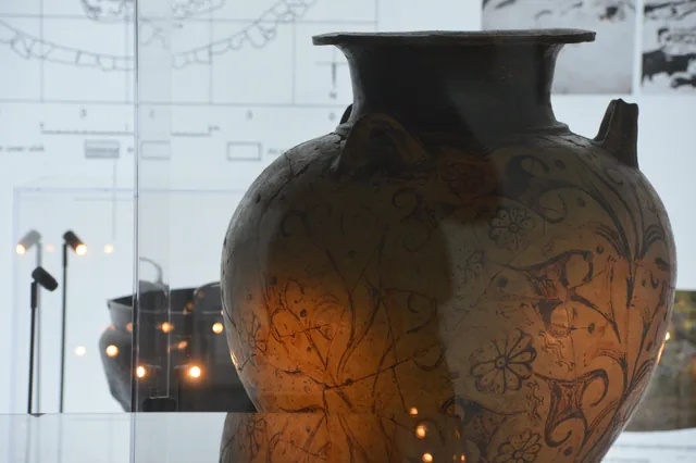 Close-up of a large painted clay vessel decorated with plant and animal motifs.