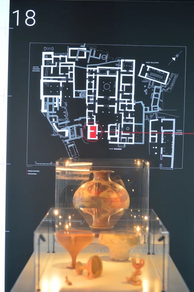 Floor plan of the Palace of Nestor displayed behind a museum case containing pottery and small artefacts.