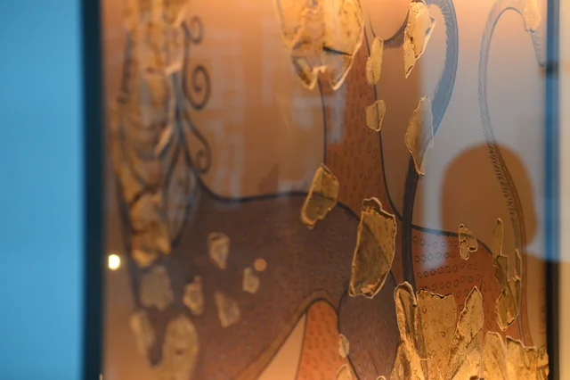 Close view of painted plaster fragments over a reconstructed feline outline in a museum display.