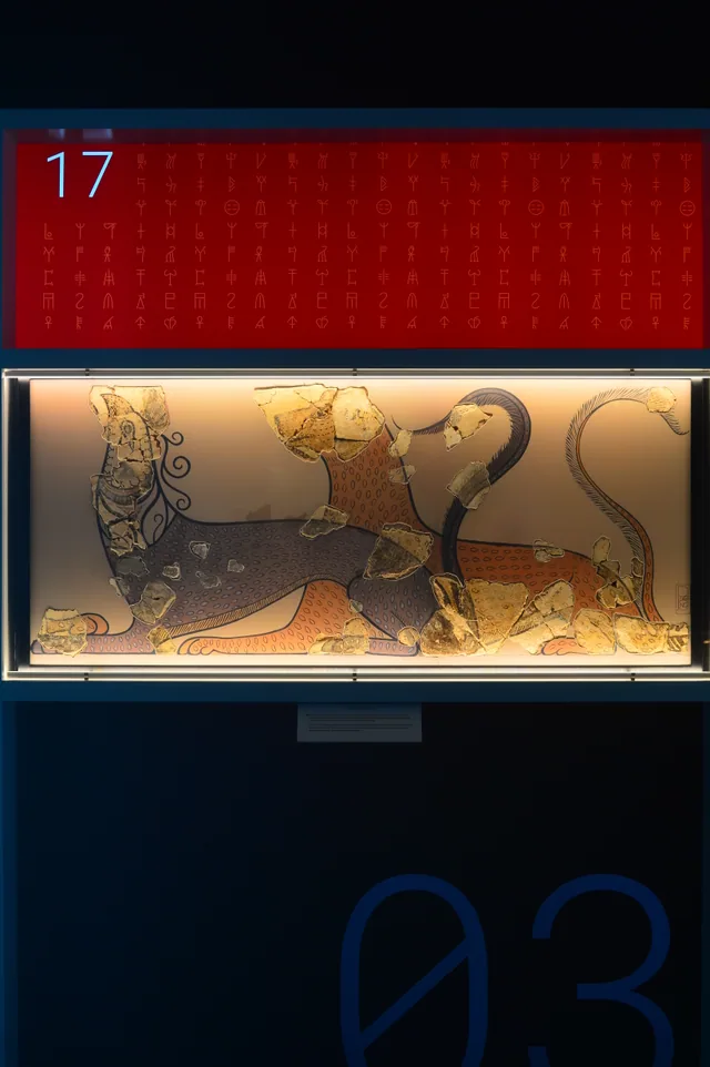 Fresco fragments set against a modern illustration of two felines, beneath red Linear B graphics.