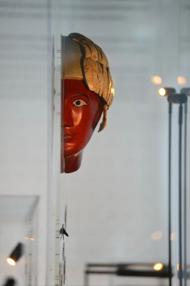 Frontal view of a reconstructed painted human head with surviving reddish and pale plaster fragments.