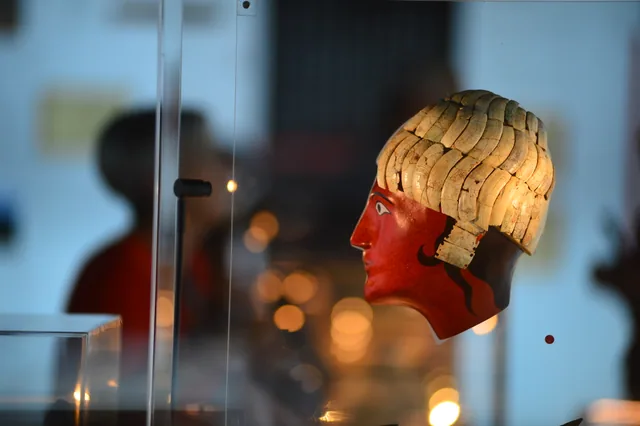 Side view of the same reconstructed painted head, showing its pale segmented hair or head covering.