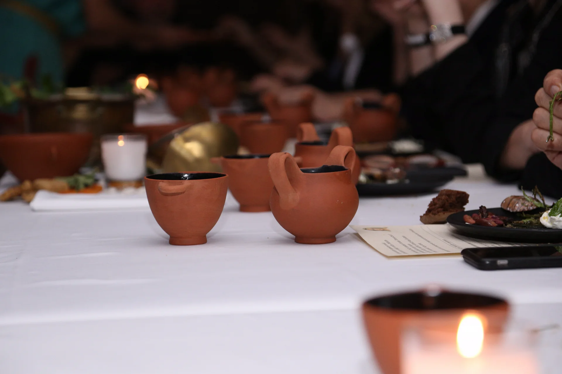 Terracotta drinking cups arranged across the candlelit private dinner table