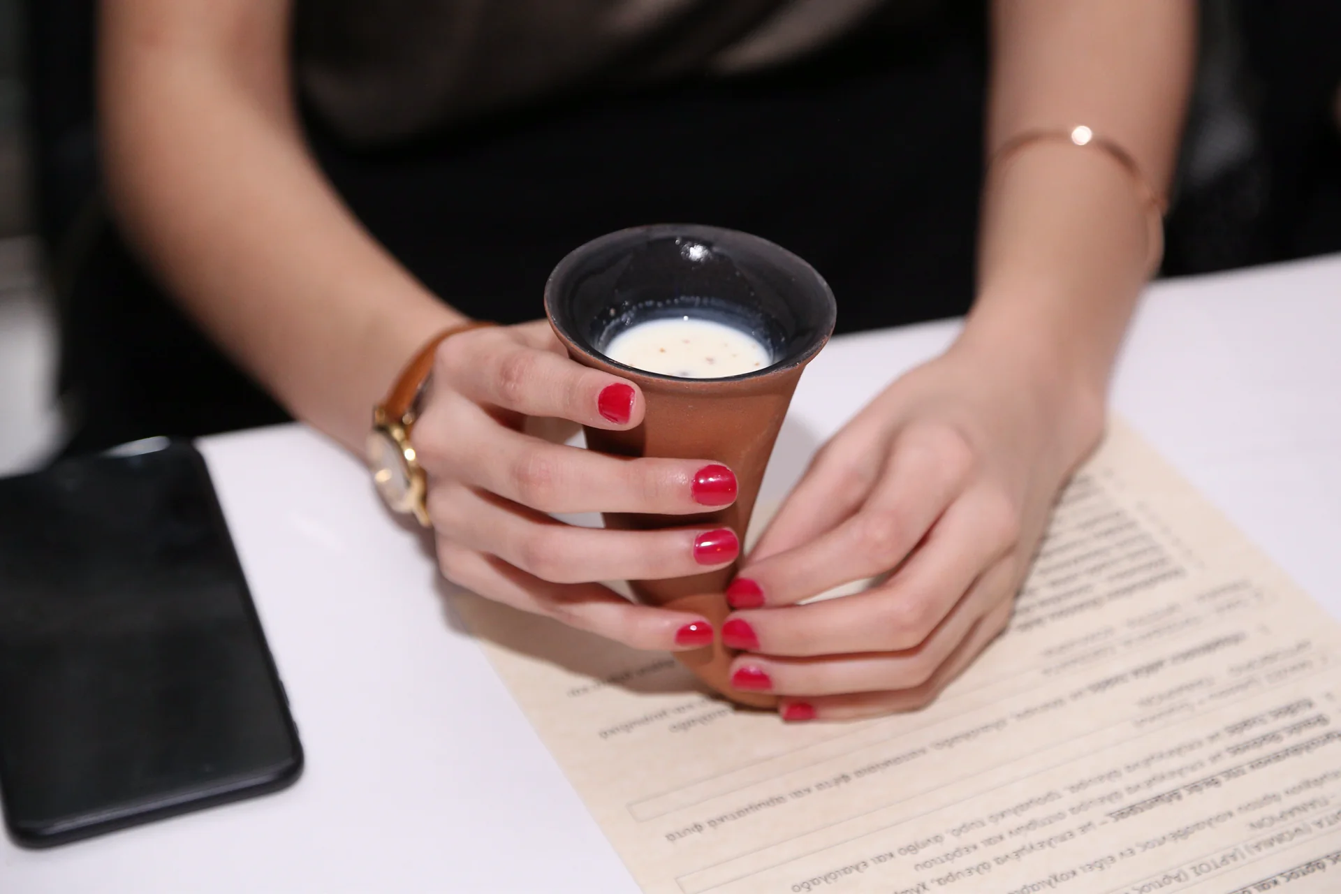 Guest holding a terracotta cup beside the printed dinner menu
