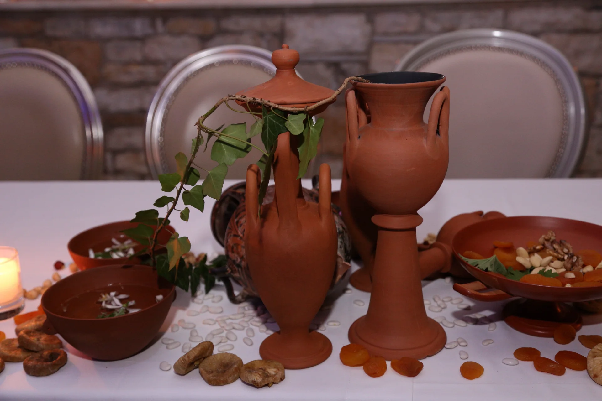 Reconstructed terracotta jugs surrounded by bowls, dried fruit, nuts and ivy
