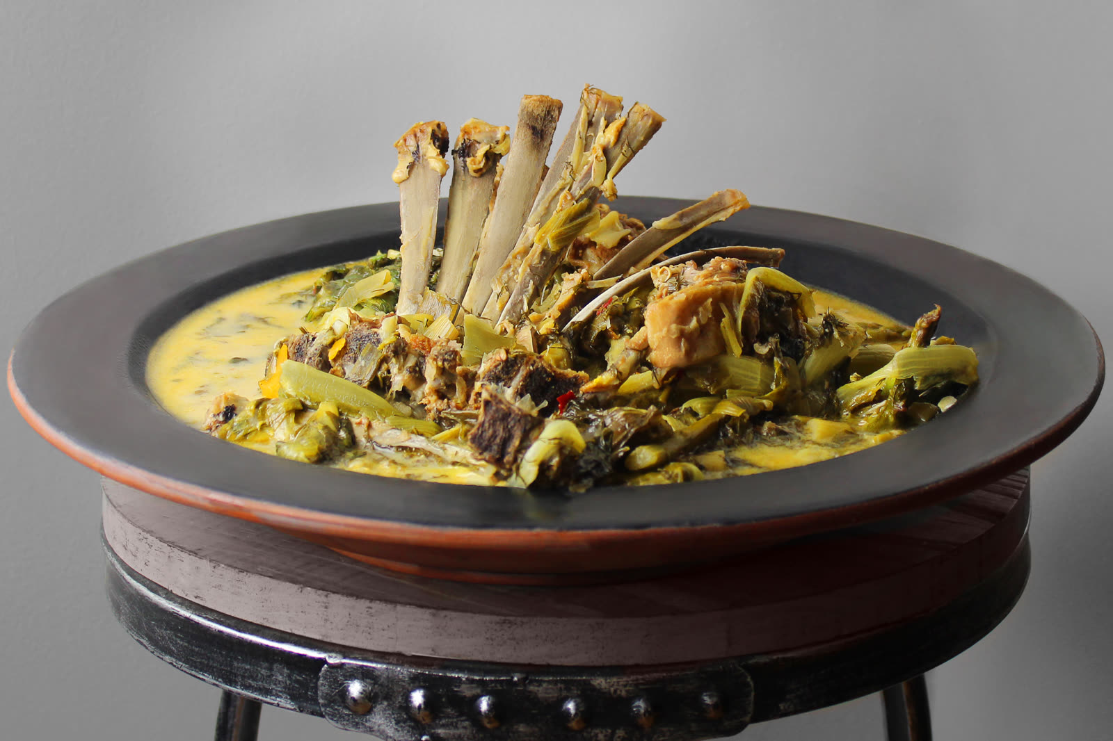Slow-cooked meat and greens presented in a wide serving vessel for the Mykonos event