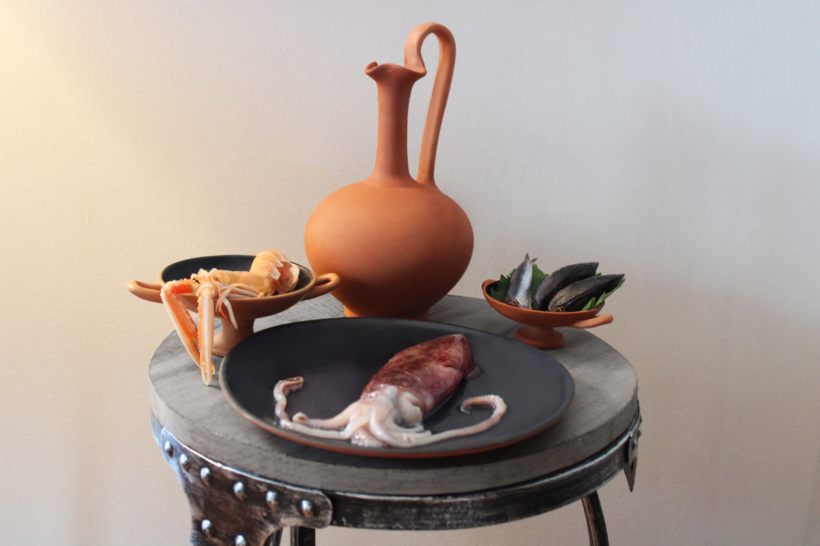 Squid and shellfish arranged beside a terracotta amphora for the mythological menu