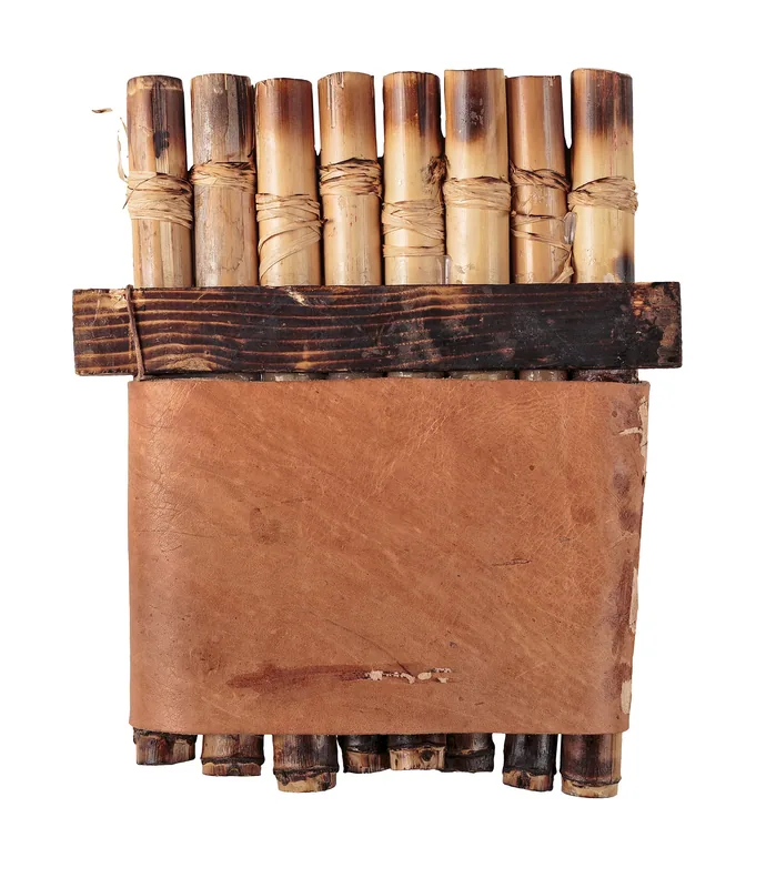 Eight cane panpipes bound together with cord, a wooden brace and a broad leather cover