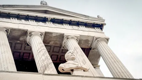 Official programme still from Troy Story: The Schliemann Legacy showing a neoclassical facade and statue